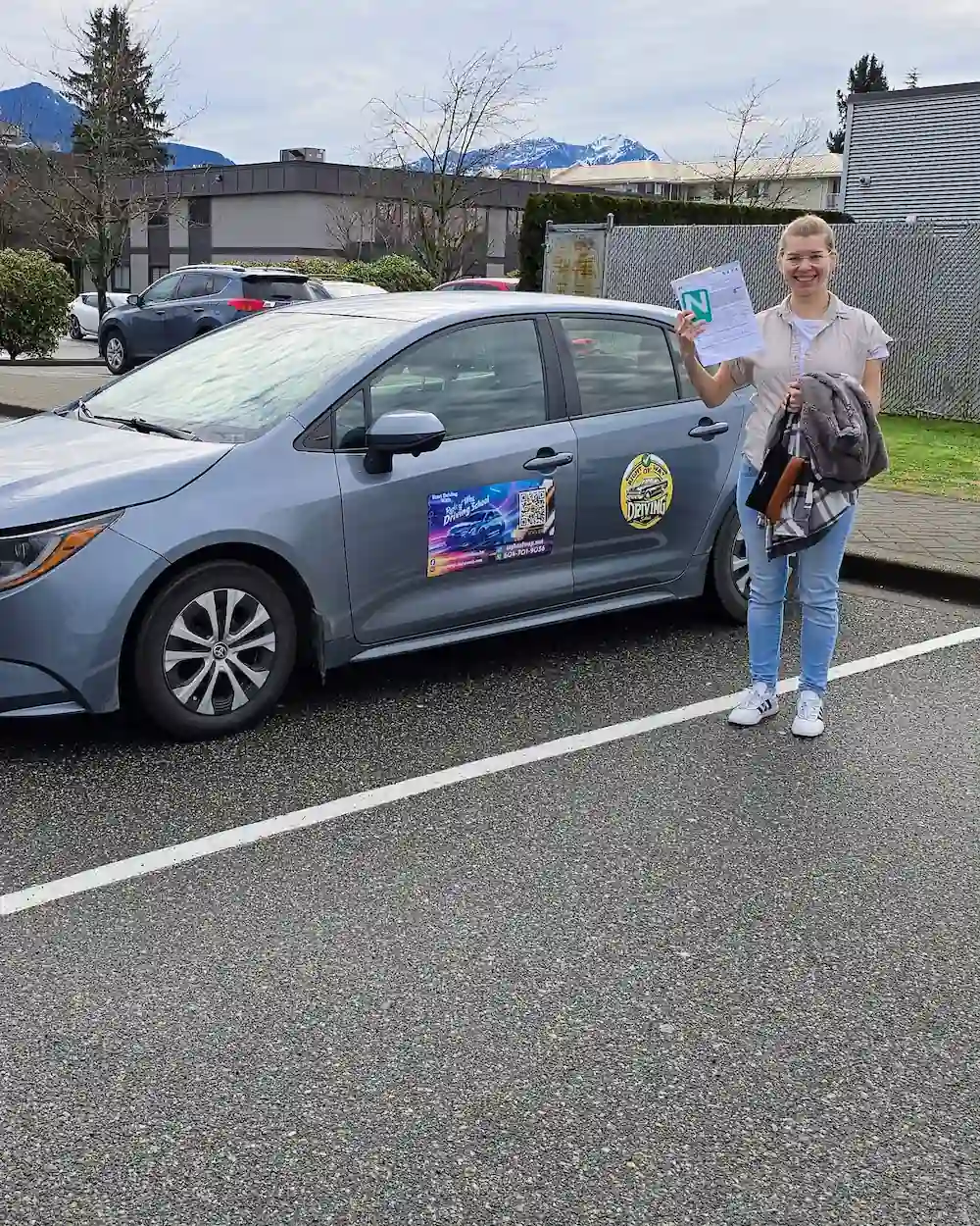 Anastasiia Konovalenko holding her passing paperwork beside the Right of Way training car